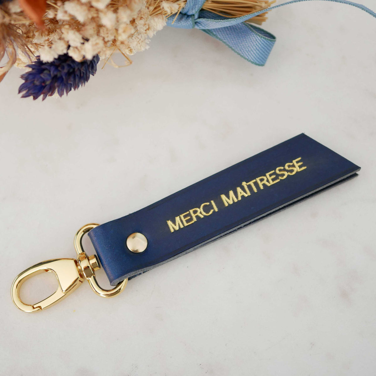 Porte-clés Atelier Guillocher en cuir bleu marine avec marquage doré Merci Maîtresse et attache dorée