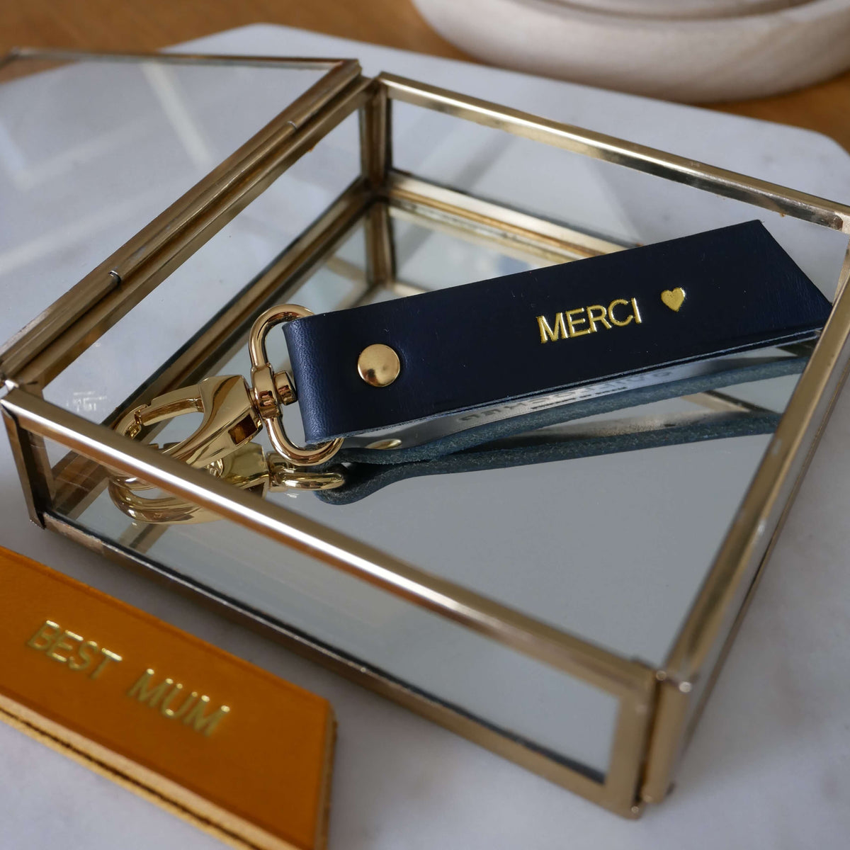 Porte-clés RUBAN Atelier Guillocher en cuir bleu marine avec marquage à chaud doré et attache métallique dorée